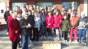 Zdjęcie grupowe uczniów przed szkołą, wraz z hodowcą gołębi; uczniowie mogli wypuszczać je w świat jako symbol pokoju, wypowiadając życzenie dla wszystkich dzieci