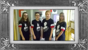 Cztery uczennice w biało-czerwonych opaskach na przedramionach i czarnych t-shirtach z nadrukowanymi białym drukiem podobiznami bohaterek i bohaterów podpisanych imieniem i nazwiskiem wraz z ich pseudonimami